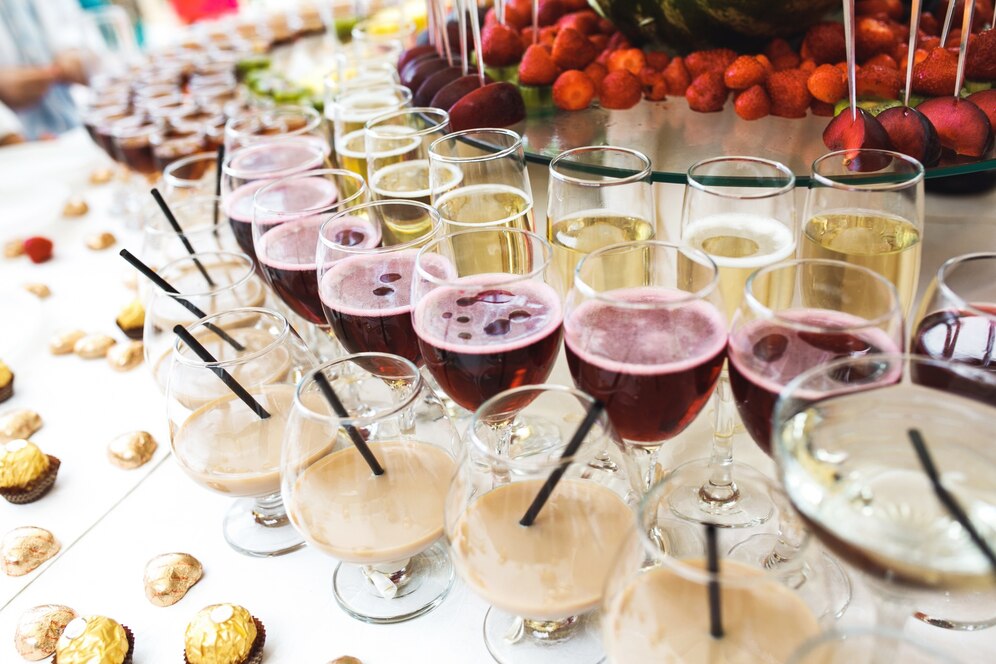 Assorted event glassware with wine, cocktails, and beverages displayed on a catering table, showcasing premium glassware and drinkware rentals from One Party Rentals.