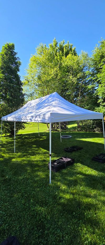 White outdoor canopy tent set up on grass with trees in the background for party